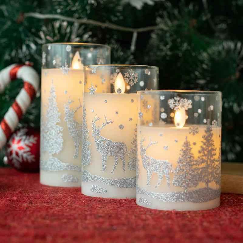 LED Christmas glass candles in decorative glass cups with winter scene design, creating a festive ambiance.