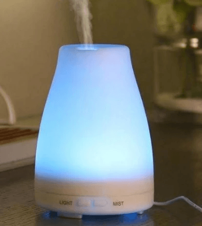 Mini Ultrasonic Aromatherapy Humidifier emitting mist with soft blue light in an elegant design.
