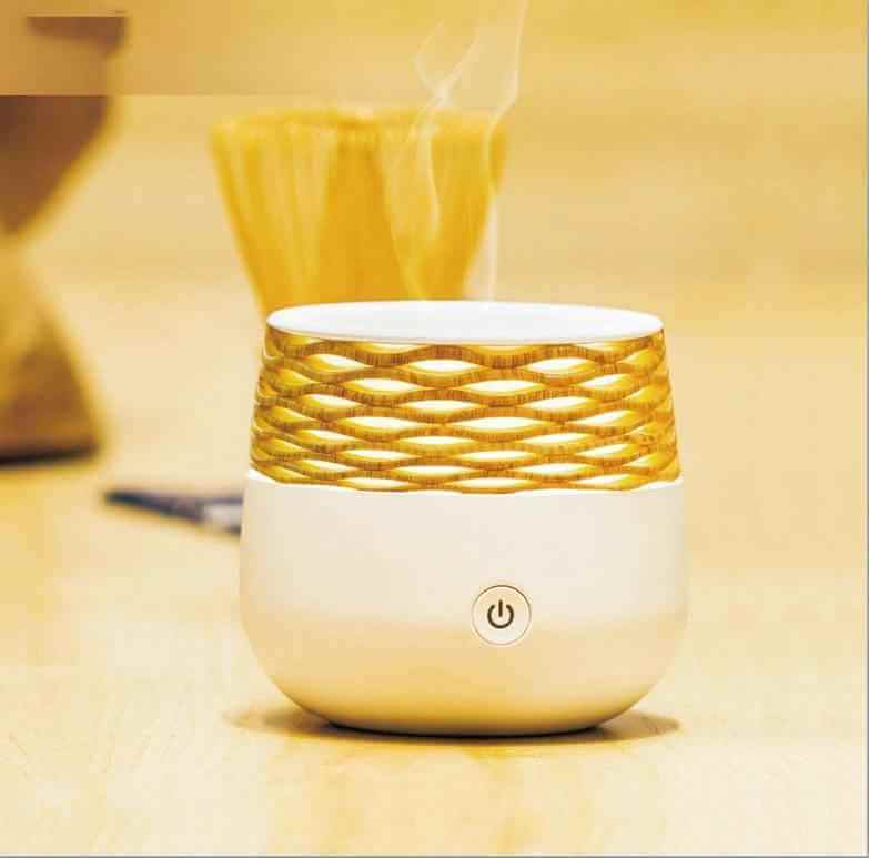 Portable ultrasonic aromatherapy diffuser with bamboo design, releasing soothing mist for relaxation.