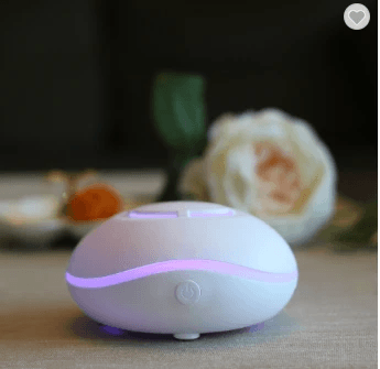 Car Humidifier and Aromatherapy Diffuser on a table with flowers, designed for a refreshing driving experience.