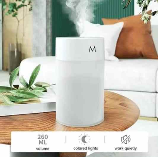 Ultrasonic air humidifier diffuser releasing mist on a wooden table with plants, showcasing modern design and features.