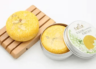 Natural plant-based hair soap in a circular bar on a wooden dish with a silver tin container.