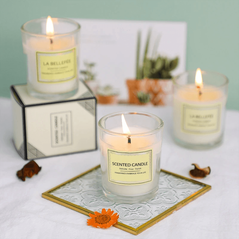 Small glass cup aromatherapy soy wax candles with burning wicks, elegantly displayed on a decorative tray.
