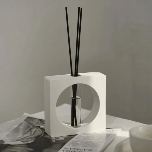 Geometric aromatherapy diffuser on a table with black reeds, stylish modern decor for a soothing fragrance experience.