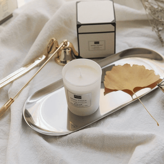 Handmade aromatherapy candle displayed on a silver tray with decorative items and packaging.
