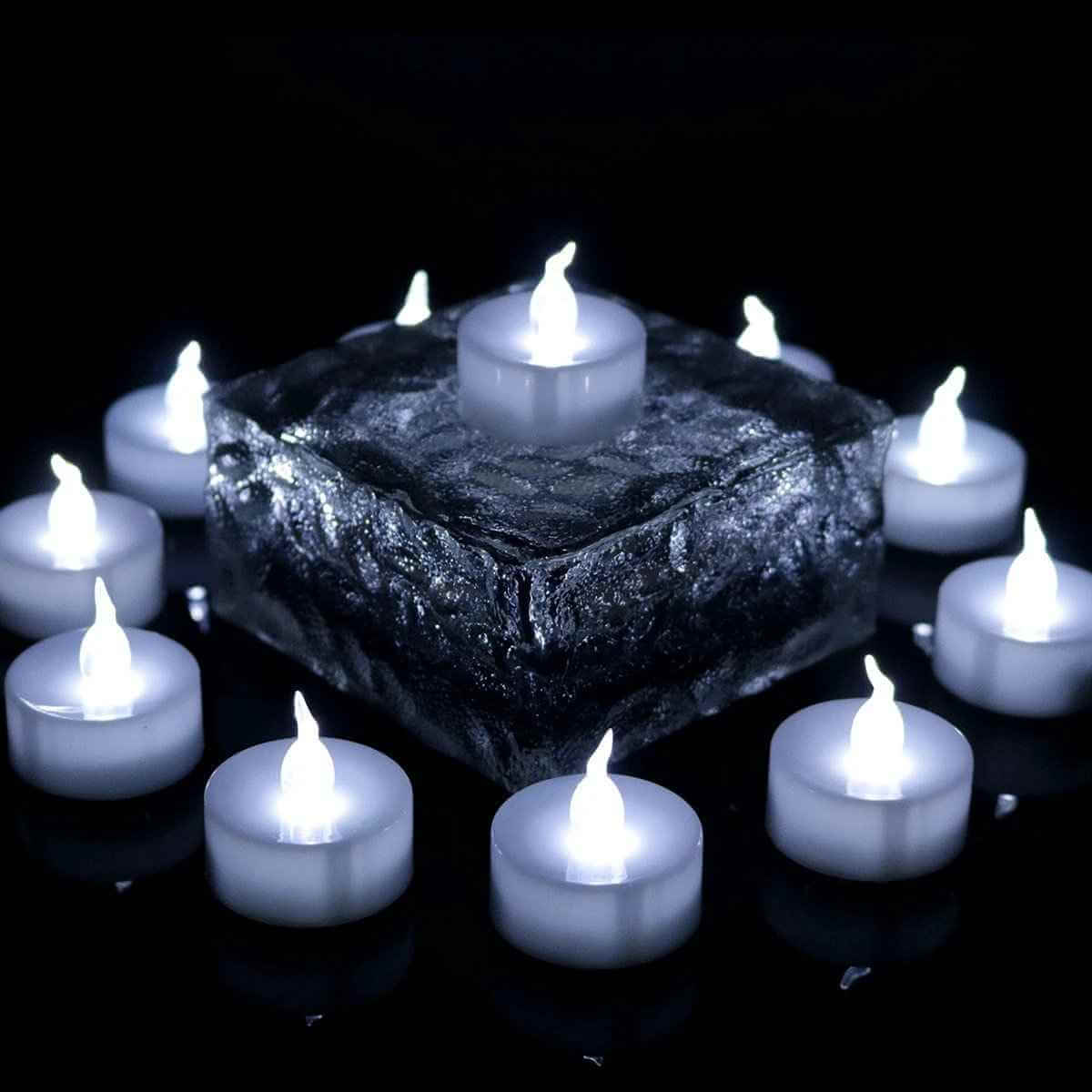 Electronic tea light candles arranged around a glass centerpiece with a flickering LED flame, perfect for festive decor.
