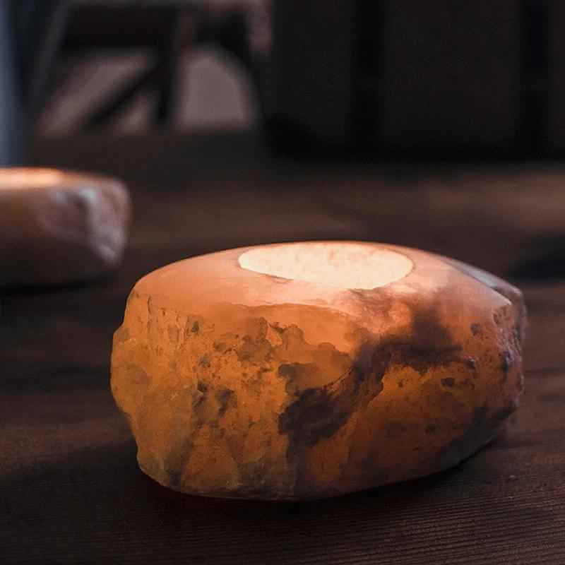 Unique stone aromatherapy candle holder lit with a warm glow, showcasing its textured surface and artistic shape.