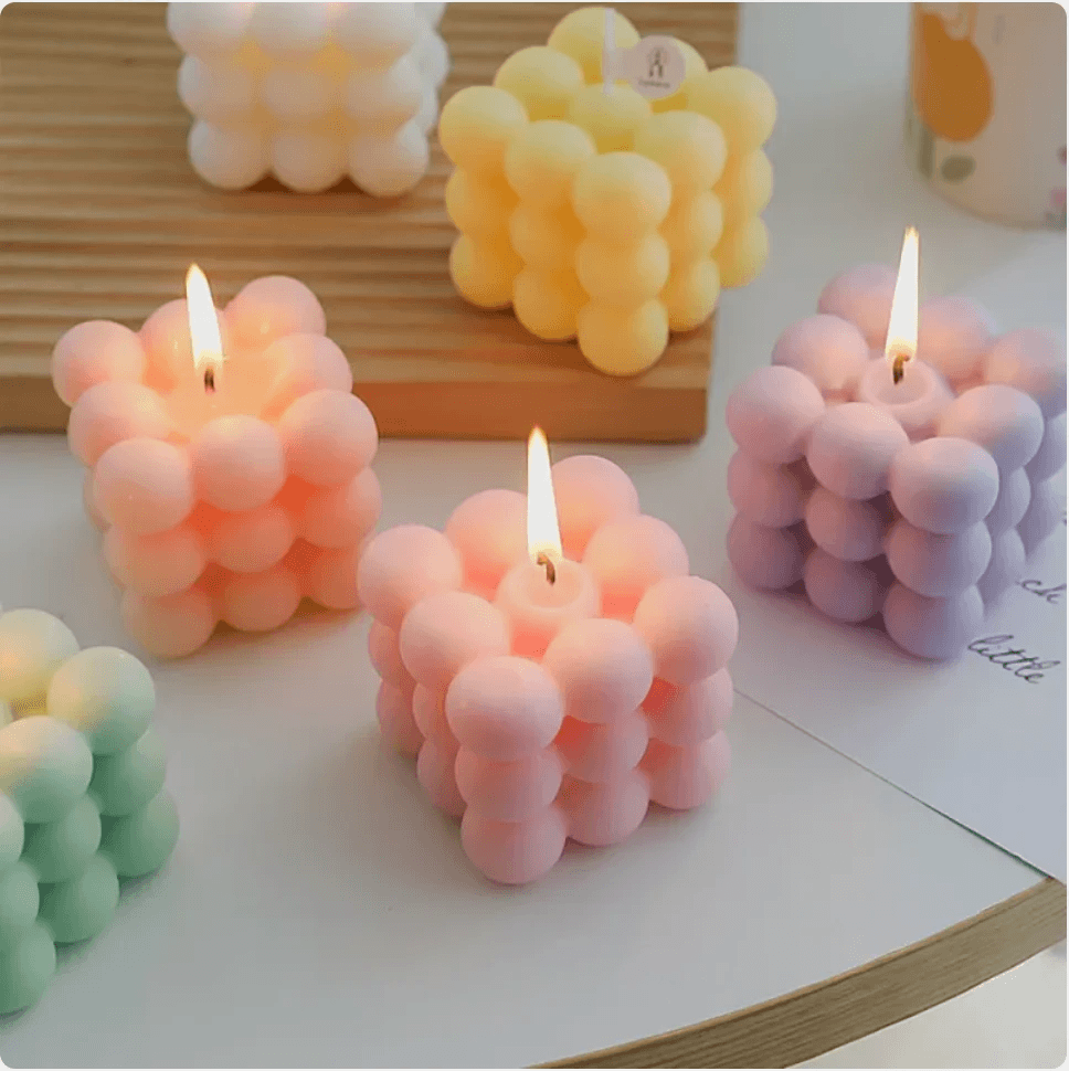 Colorful geometric aromatherapy candles in soft pastel shades, emitting a warm glow, perfect for decor or gifting.
