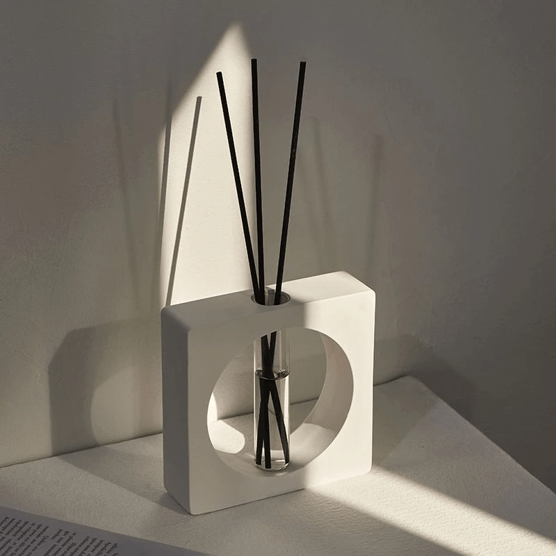 Geometric aromatherapy diffuser in stylish design with reed sticks and soft lighting on a minimalistic surface.