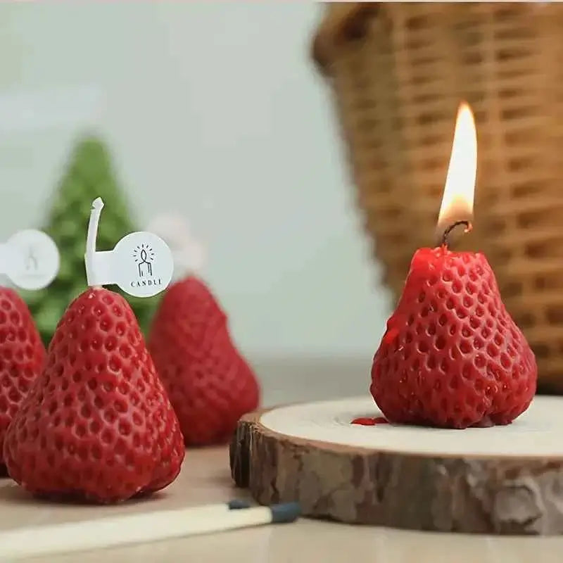 Cute strawberry candles for parties lit atop a wooden slice, perfect for festive decor and celebrations.