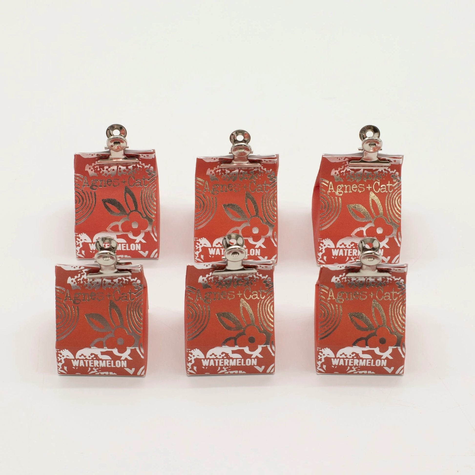 Agnes + Cat watermelon lip balm UK in compact red tins displayed in a group, showcasing vibrant packaging.