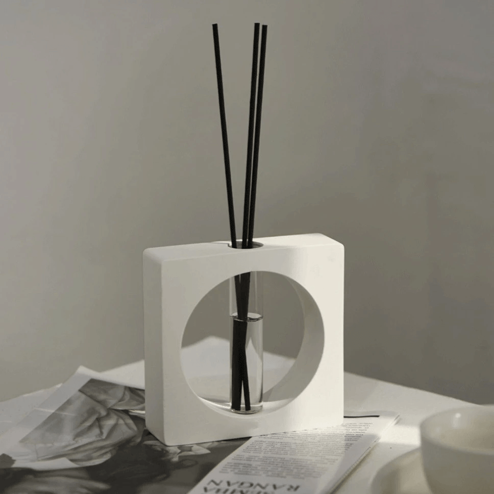 Geometric aromatherapy diffuser in white stone, featuring black reed sticks, enhancing modern decor and calming scents.