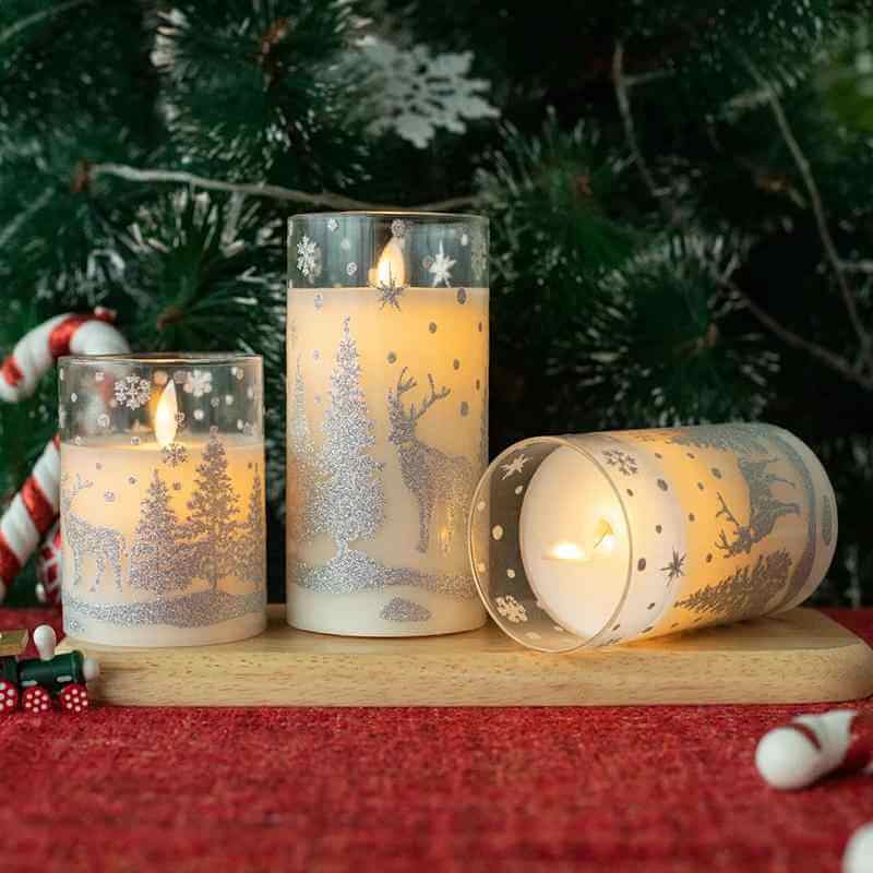 LED Christmas glass candles in decorative glass cups with winter designs and warm glow.