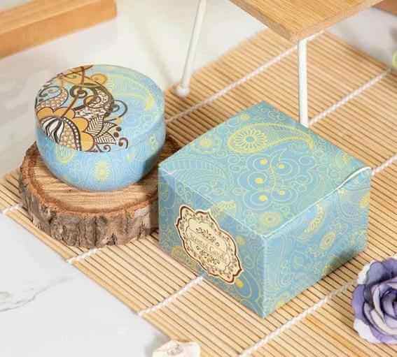 Aromatherapy essential oil candle packaging featuring decorative blue design on a wooden display.